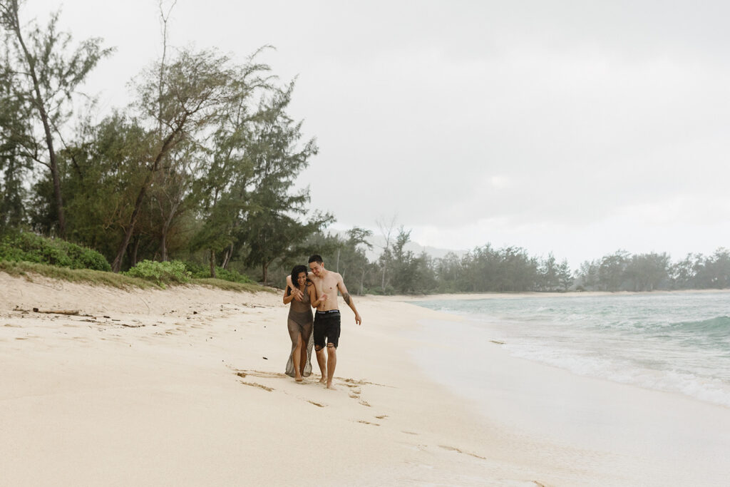 couple playing and running on a beach in oahu
