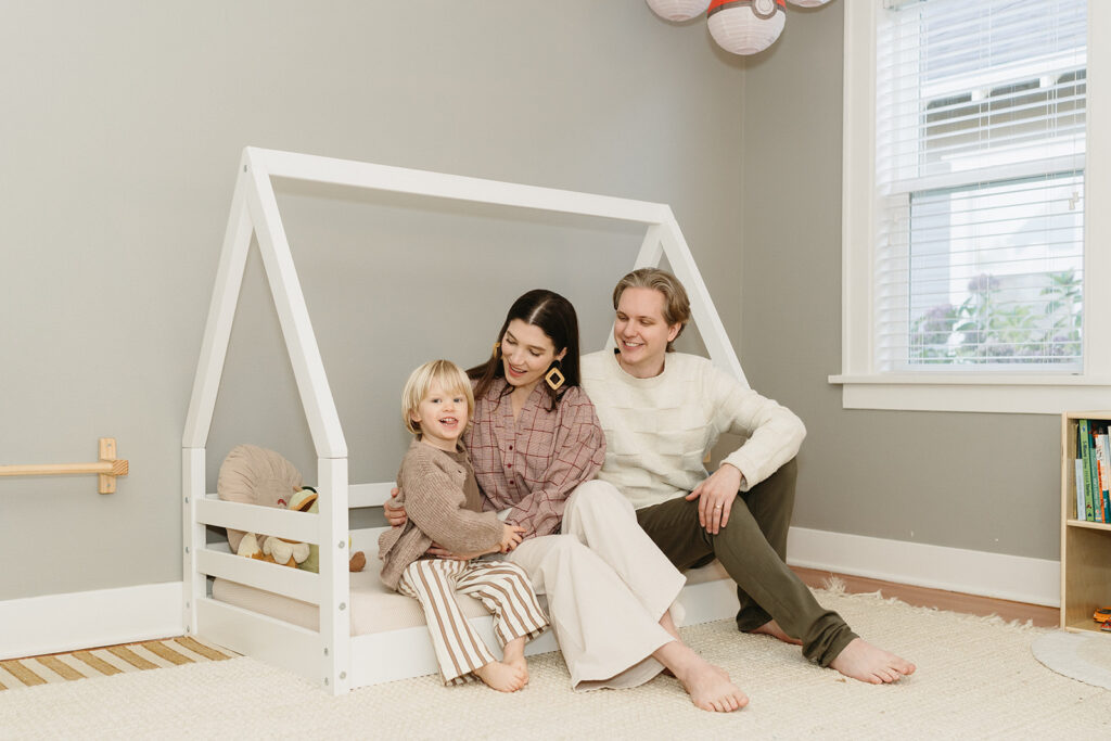 A family of three enjoying a candid moment during their in-home photo session in Portland.
