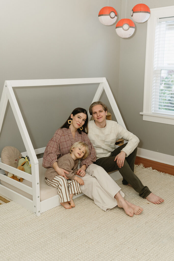 A family of three enjoying a candid moment during their in-home photo session in Portland.
