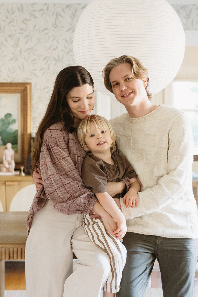 A family of three enjoying a candid moment during their in-home photo session in Portland.
