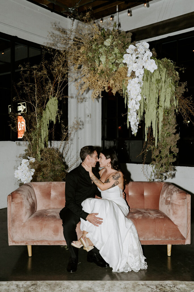 bride and groom sitting on sofa in front of floral design