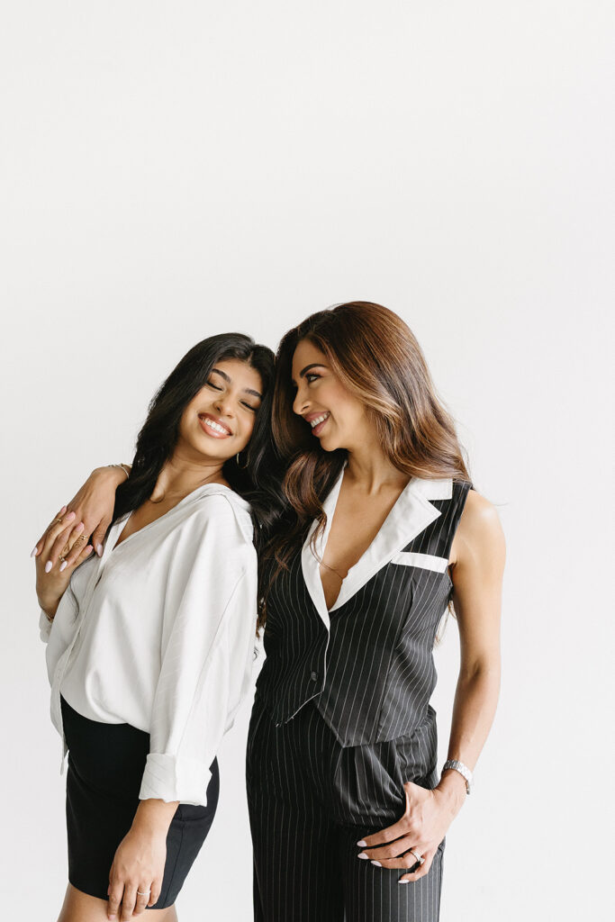 Mother and daughter posing together during a fun and fashionable photoshoot in a studio
