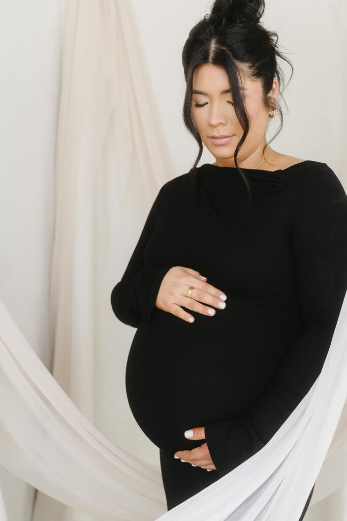 Studio maternity photo of expecting mother with soft draping and neutral tones
