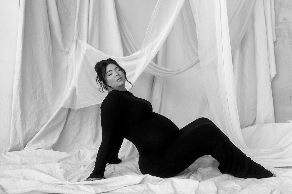 Studio maternity photo of expecting mother with soft draping and neutral tones
