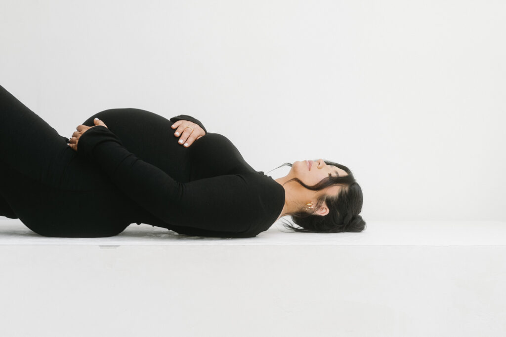 Studio maternity photo of expecting mother with soft draping and neutral tones
