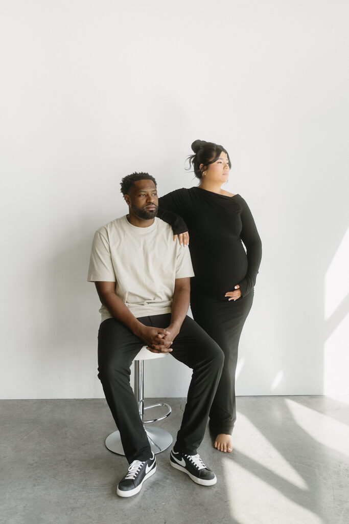 Pregnant woman holding baby bump in a clean, timeless studio setting
