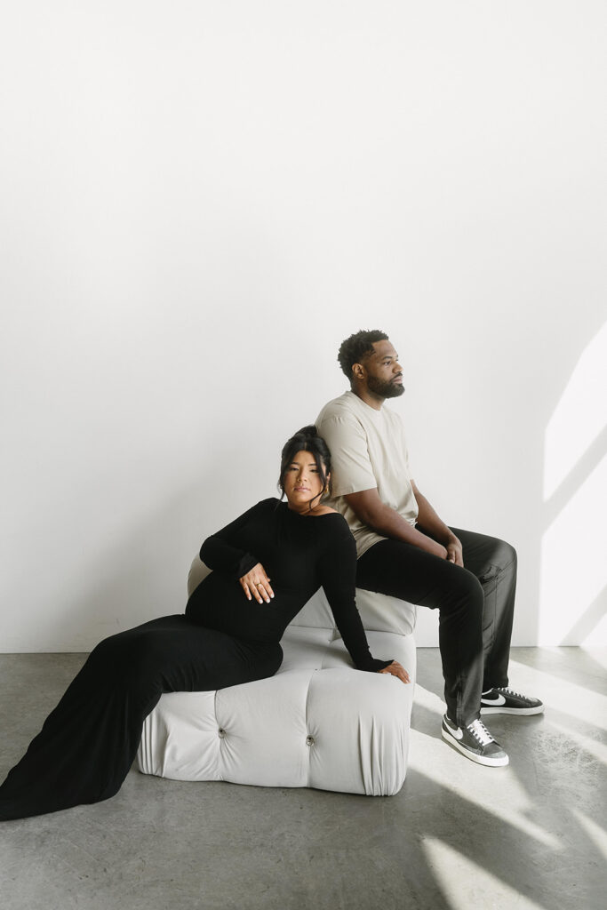 Pregnant woman holding baby bump in a clean, timeless studio setting
