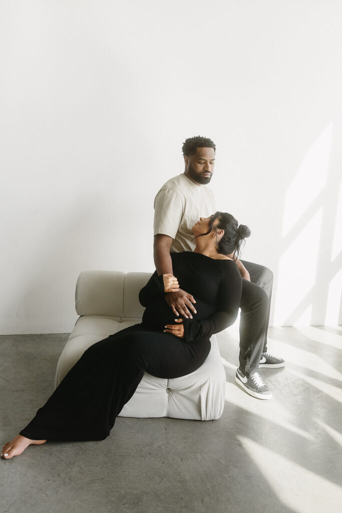 Pregnant woman holding baby bump in a clean, timeless studio setting
