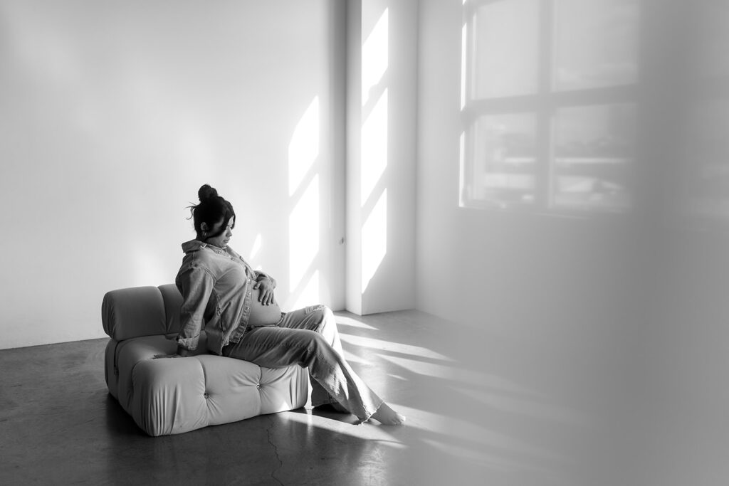 Studio maternity photo of expecting mother with soft draping and neutral tones
