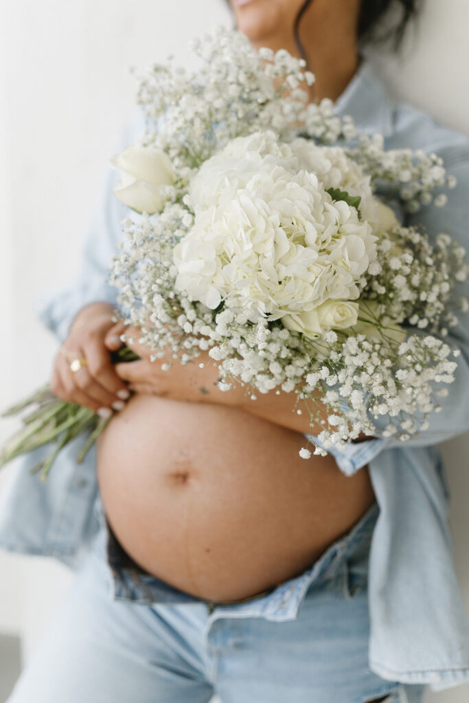 Minimalist maternity portrait with floral accents in natural light
