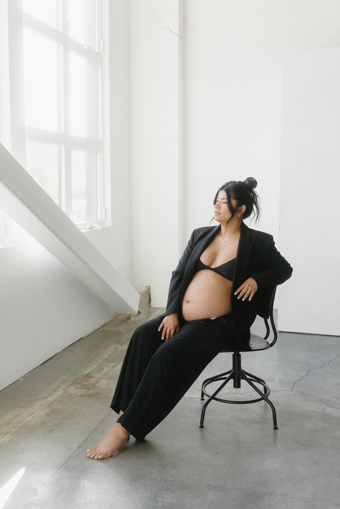 Pregnant woman holding baby bump in a clean, timeless studio setting
