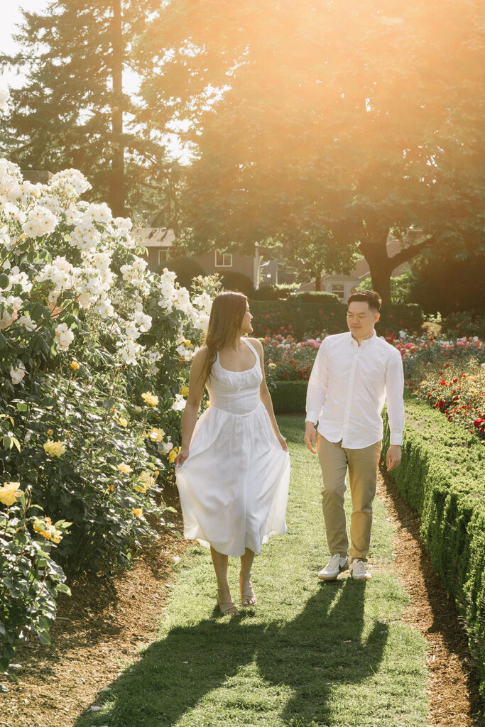 A couple walking through a blooming rose garden during their engagement session | Peninsula Rose Garden
