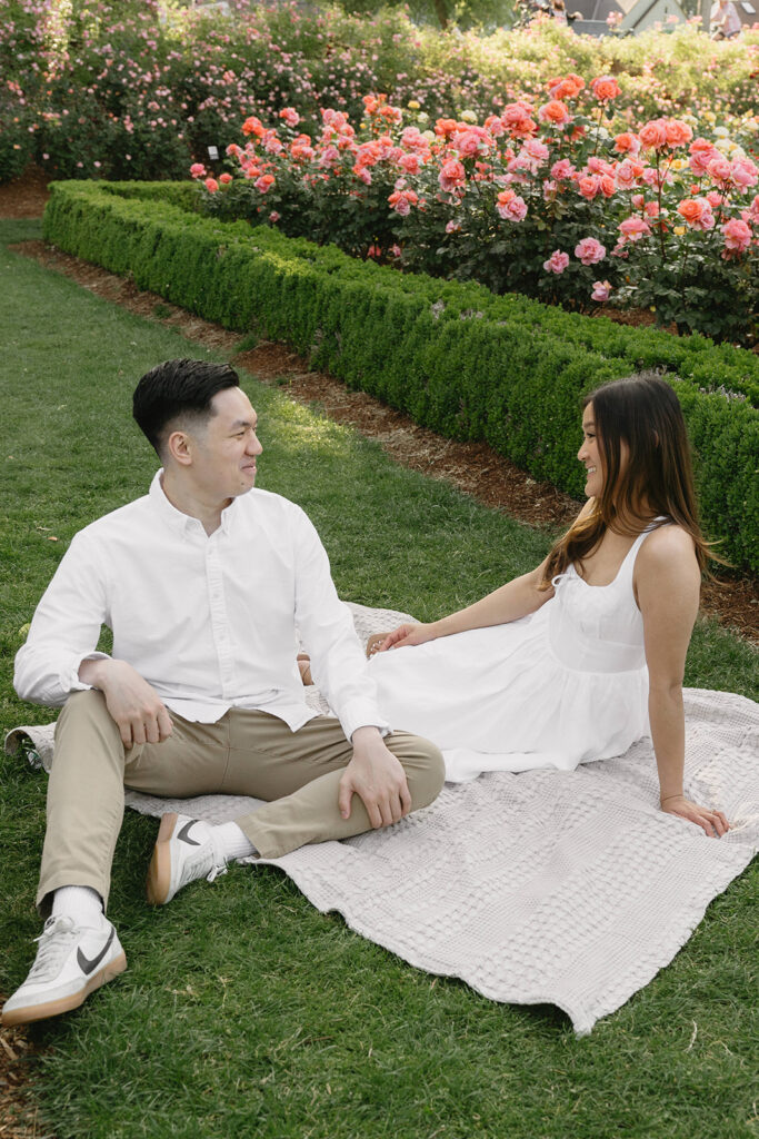 A couple walking through a blooming rose garden during their engagement session | Peninsula Rose Garden
