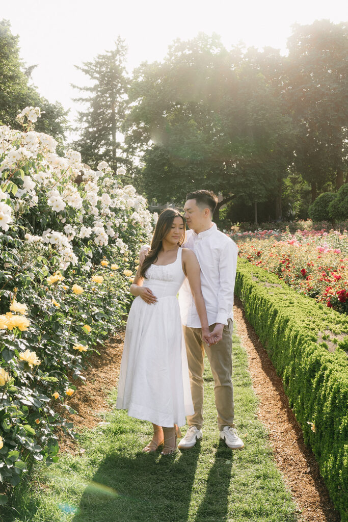 A couple walking through a blooming rose garden during their engagement session | Peninsula Rose Garden
