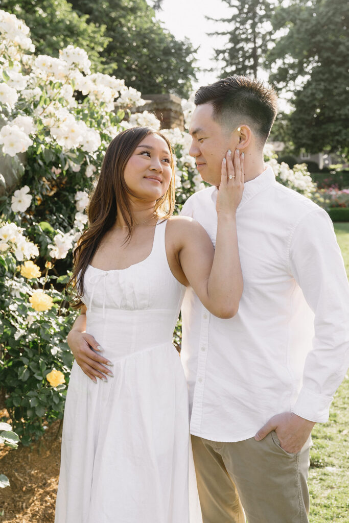 A couple walking through a blooming rose garden during their engagement session | Peninsula Rose Garden
