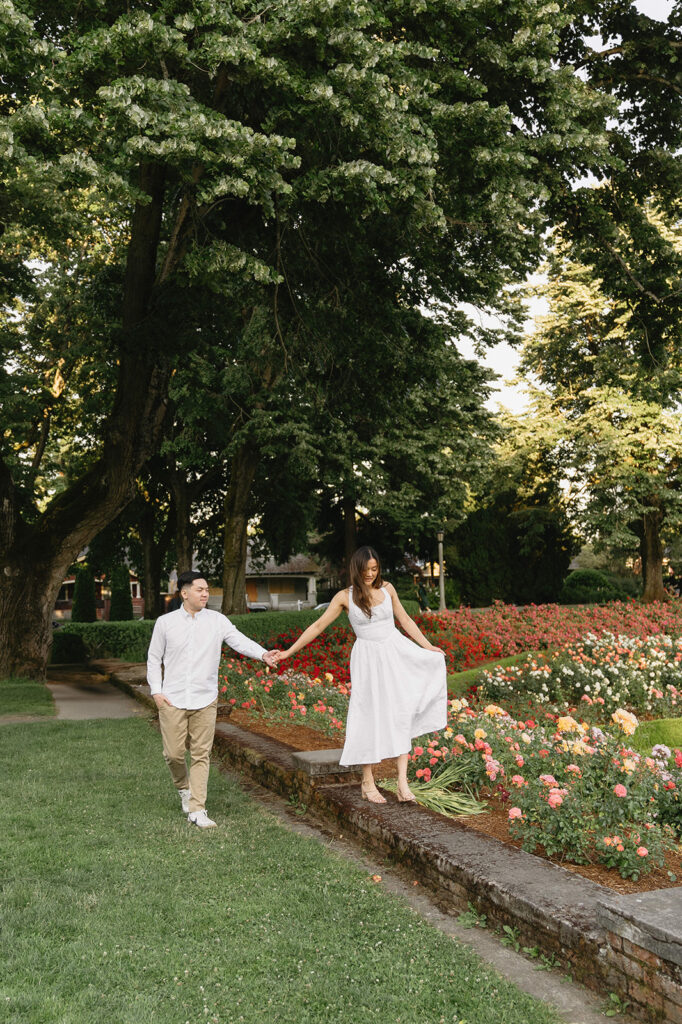 A couple walking through a blooming rose garden during their engagement session | Peninsula Rose Garden
