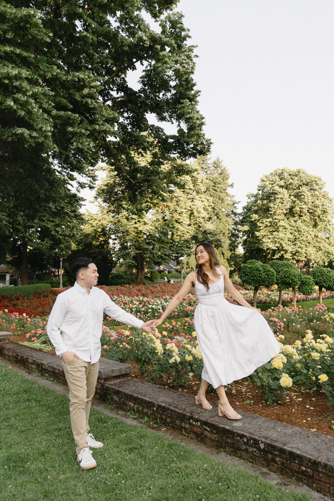 A couple walking through a blooming rose garden during their engagement session | Peninsula Rose Garden
