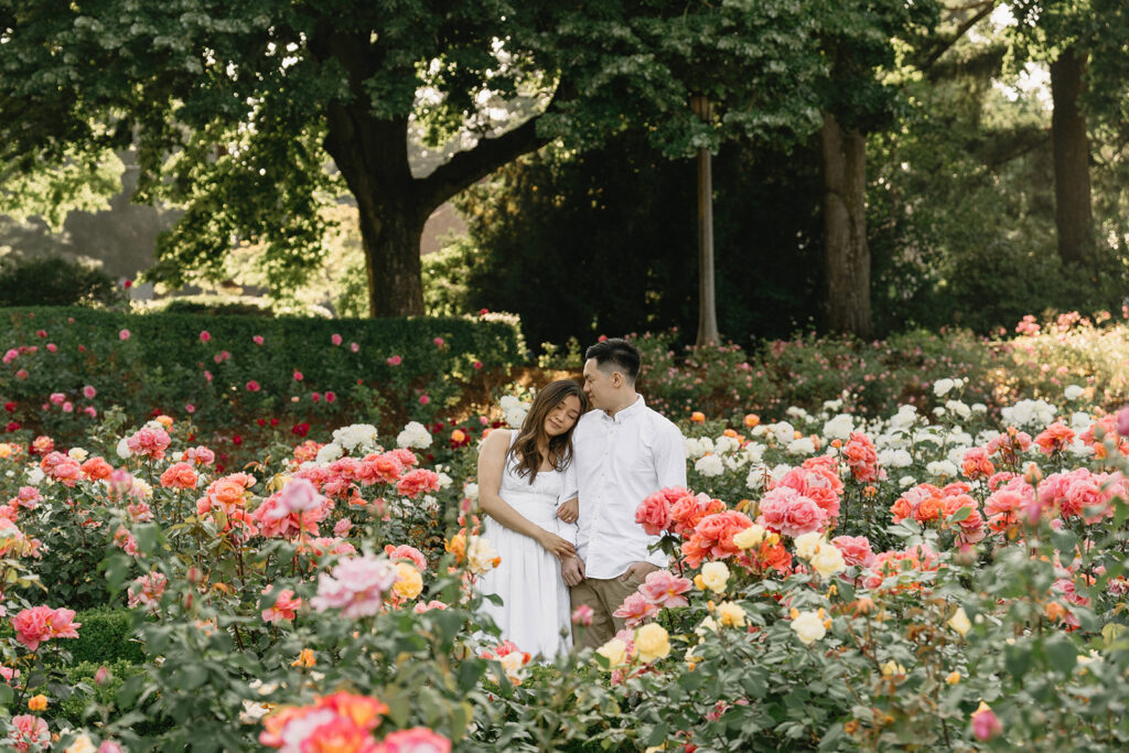 Romantic engagement photo of a couple surrounded by colorful flowers.
