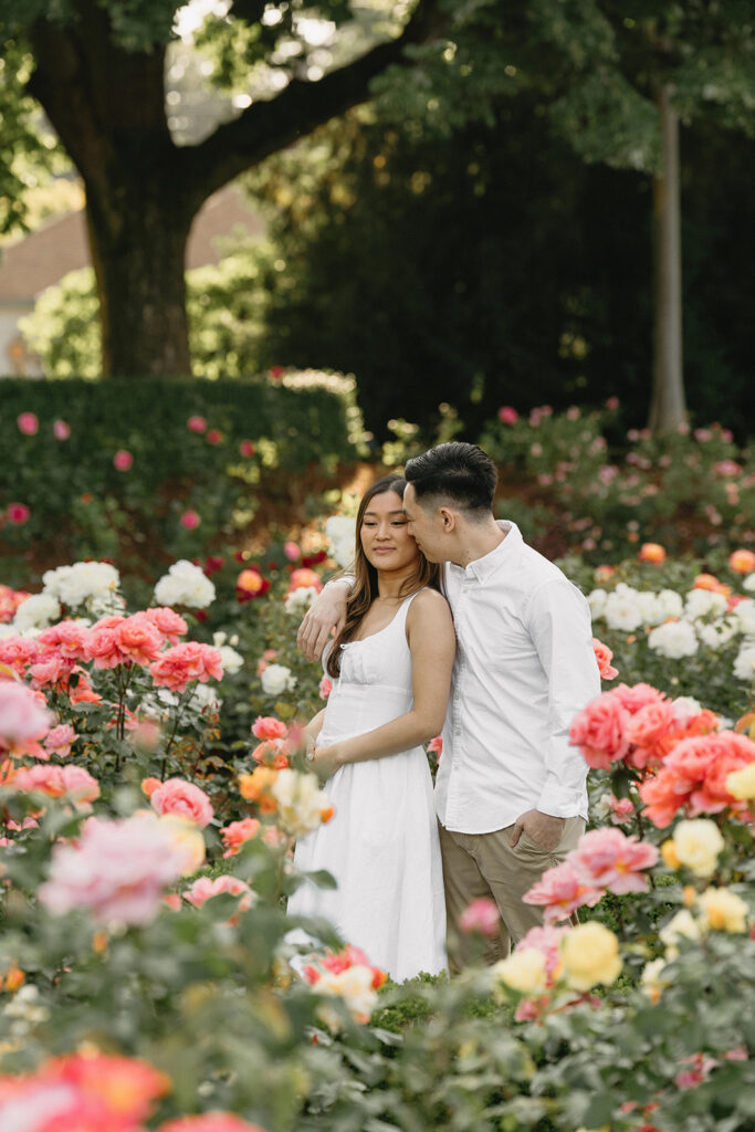 A couple walking through a blooming rose garden during their engagement session | Peninsula Rose Garden
