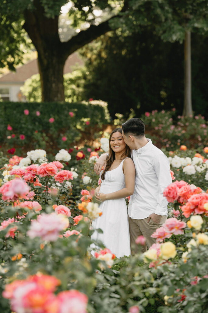 Romantic engagement photo of a couple surrounded by colorful flowers.

