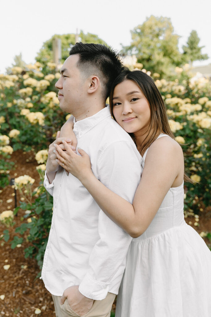 Romantic engagement photo of a couple surrounded by colorful flowers.
