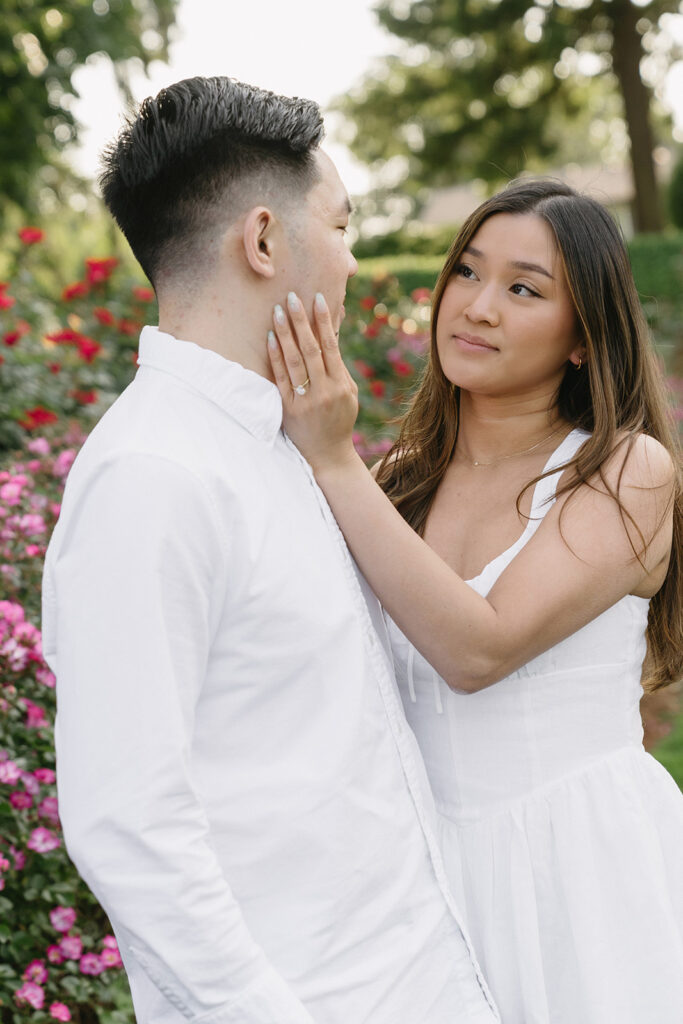 Romantic engagement photo of a couple surrounded by colorful flowers.
