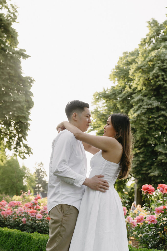 Romantic engagement photo of a couple surrounded by colorful flowers.
