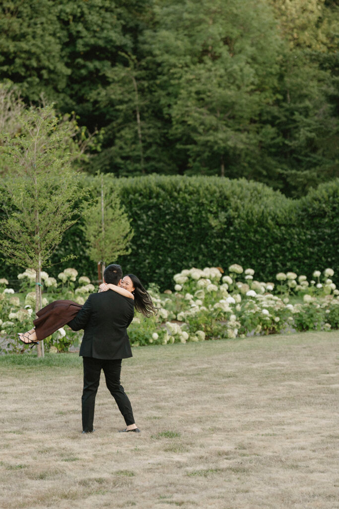 Romantic engagement photo surrounded by blooming hydrangeas at a vineyard estate
