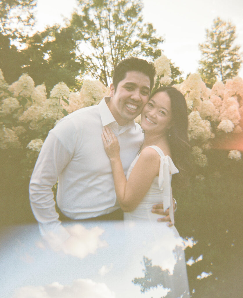 Romantic engagement photo surrounded by blooming hydrangeas at a vineyard estate
