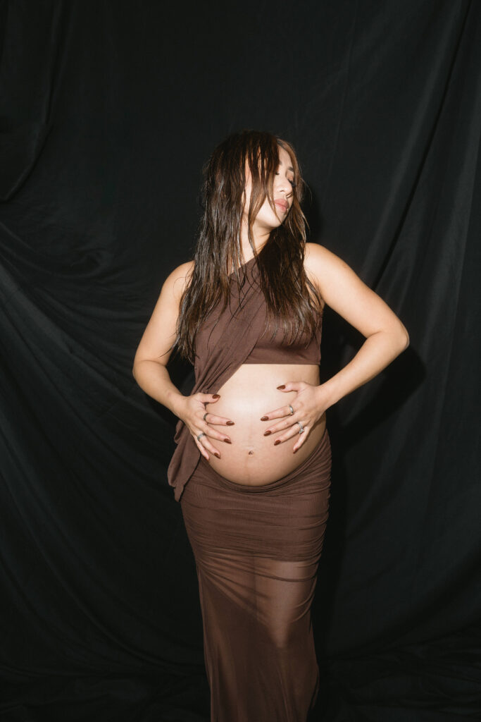 Expecting parents sharing a candid moment in a minimalist studio space.
