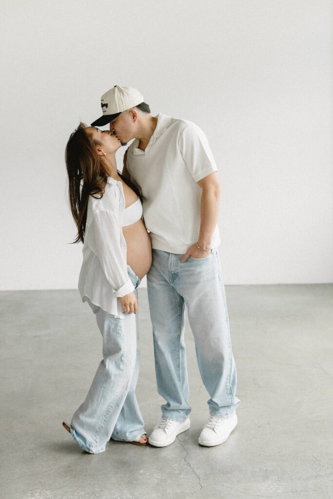 Creative maternity photoshoot with artistic draping and warm lighting.
