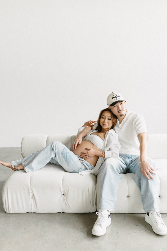 Creative maternity photoshoot with artistic draping and warm lighting.
