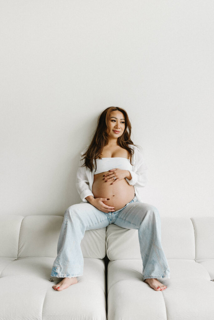Creative maternity photoshoot with artistic draping and warm lighting.
