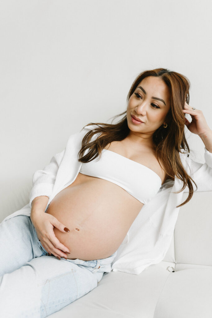 Creative maternity photoshoot with artistic draping and warm lighting.
