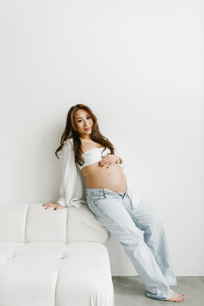 Creative maternity photoshoot with artistic draping and warm lighting.

