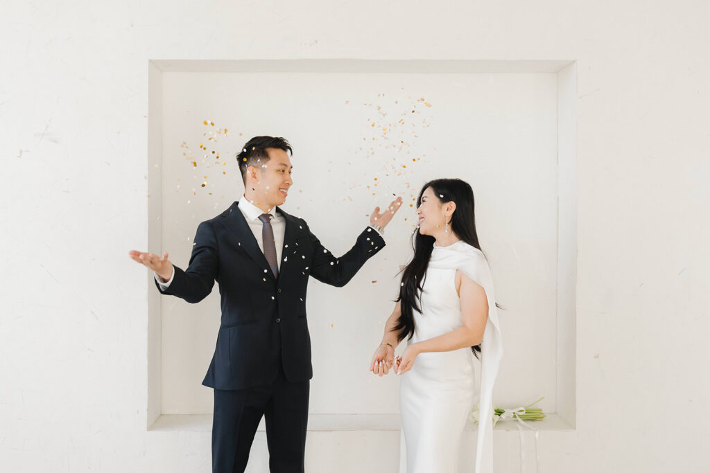 Elegant couple standing together in a minimalist studio with soft natural light and neutral tones.
