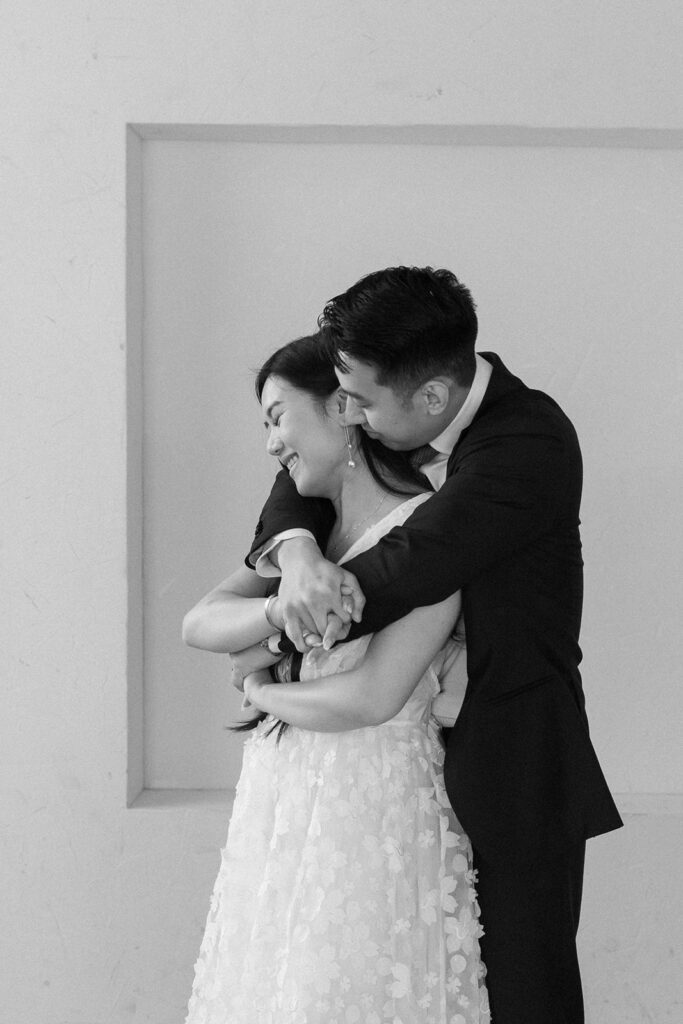 Bride and groom sharing a kiss during timeless and elegant pre-wedding portraits in studio in Portland at Cream Creative Space with soft natural light and minimal white backdrop.
