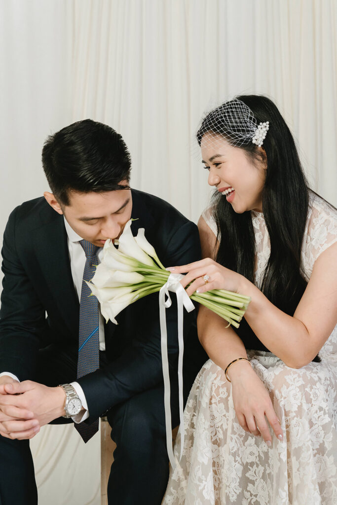 Bride holding a bouquet of white flowers while posing for timeless indoor wedding portraits.
