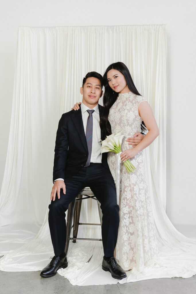 Bride holding a bouquet of white flowers while posing for timeless indoor wedding portraits.
