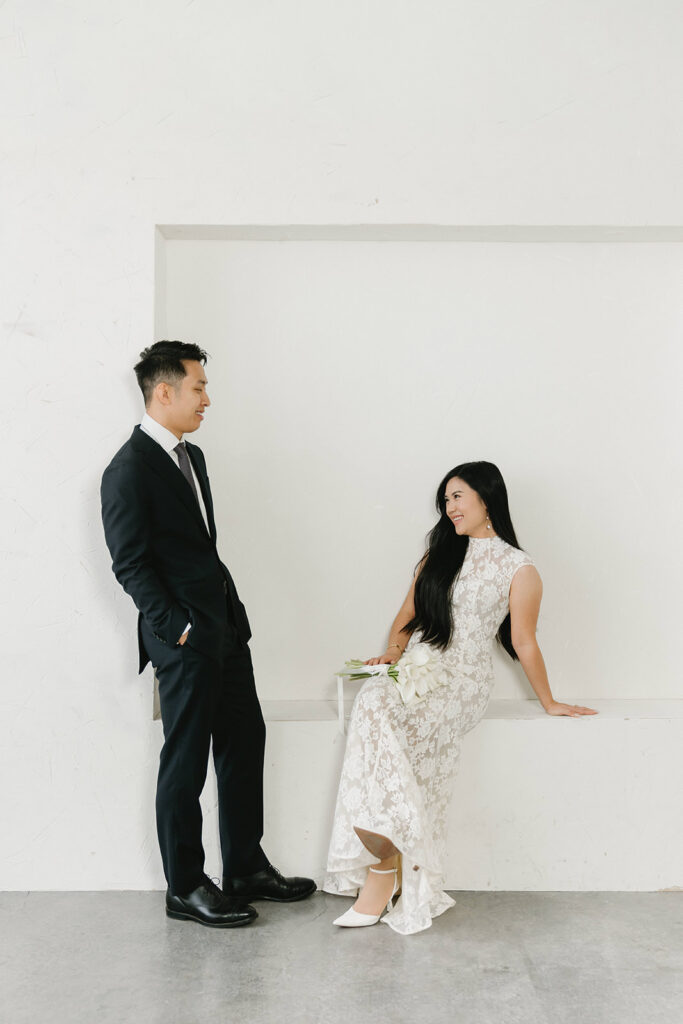 Couple embracing in a modern studio space with clean architectural details and simple styling.
