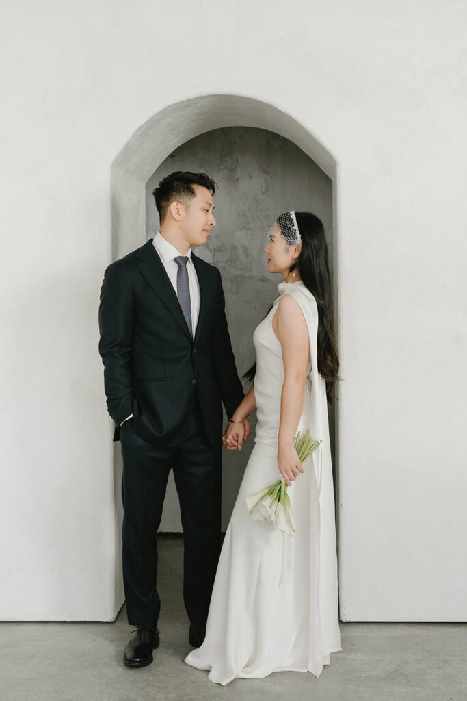 Couple embracing in a modern studio space with clean architectural details and simple styling.
