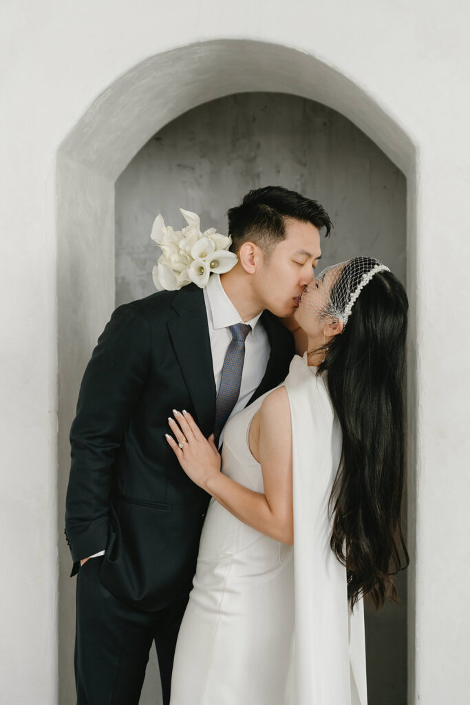 Bride and groom sharing a kiss during timeless and elegant pre-wedding portraits in studio in Portland at Cream Creative Space with soft natural light and minimal white backdrop.
