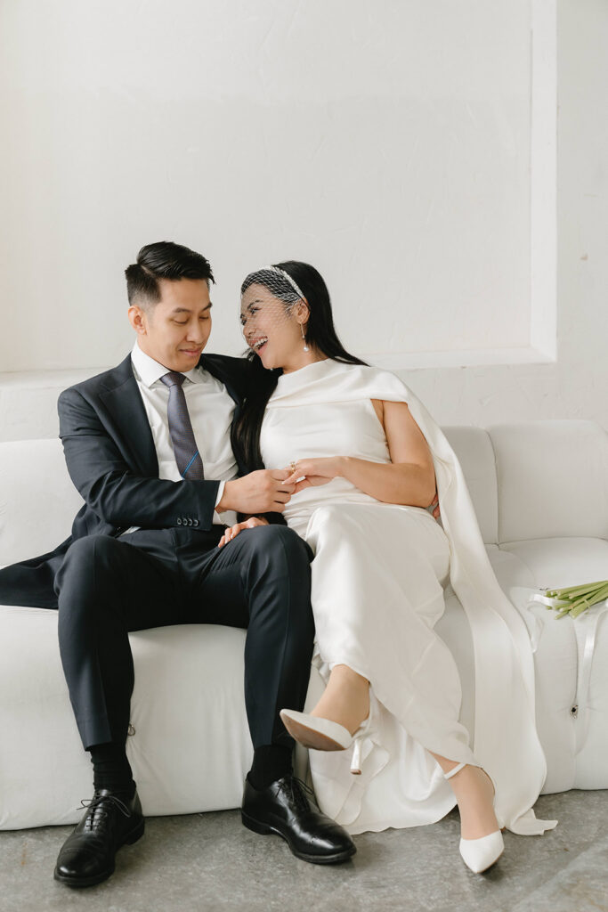 Elegant couple standing together in a minimalist studio with soft natural light and neutral tones.
