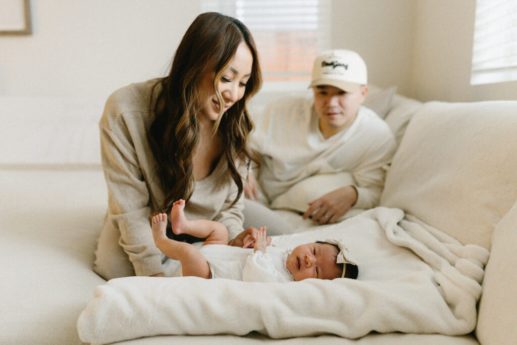 Mother gently holding her sleeping newborn during a calm in home newborn photoshoot by the window
