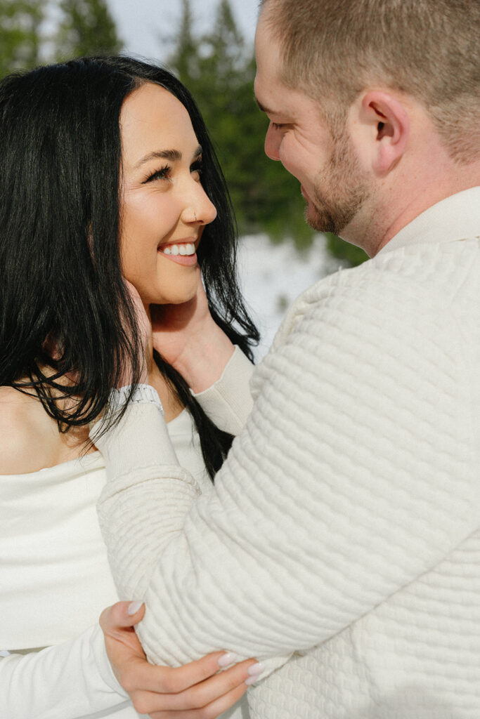 Couple standing together in a snowy mountain landscape during an engagement session
