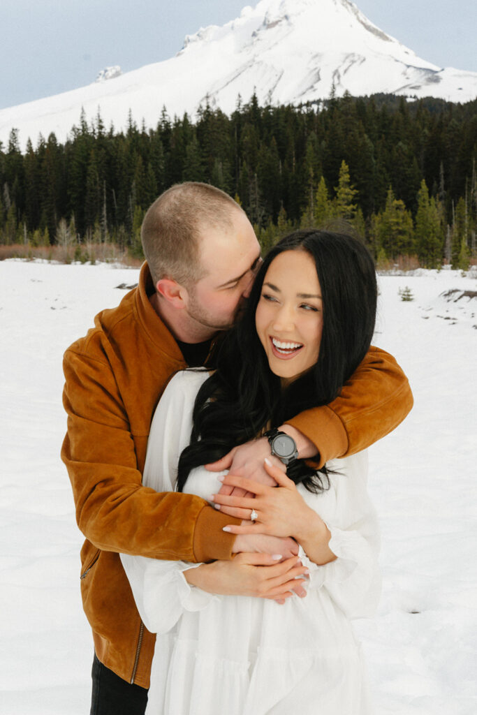 Couple standing together in a snowy mountain landscape during an engagement session
