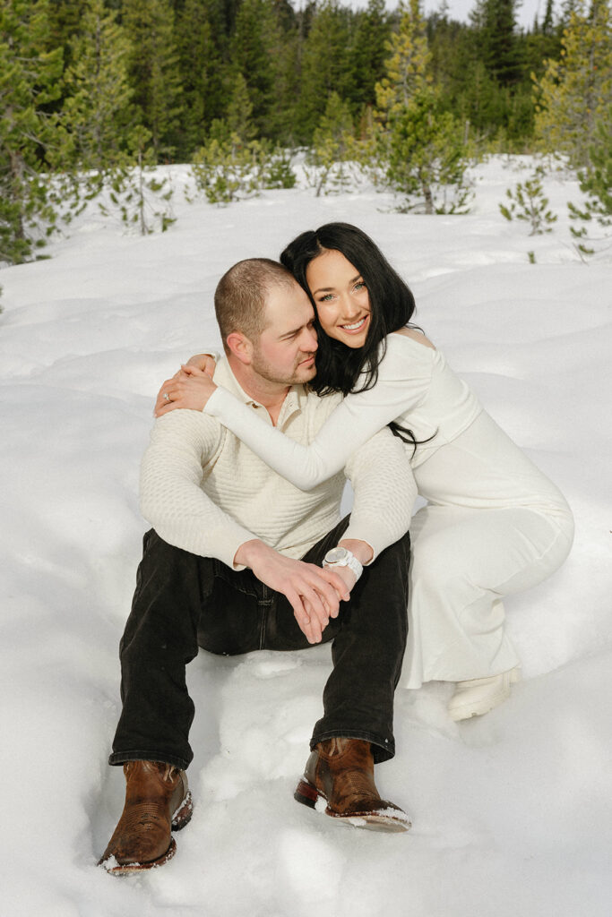 Candid moments between a couple in a winter forest setting with fresh snowfall

